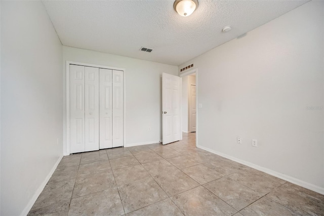 unfurnished bedroom featuring a closet, light tile flooring, and a textured ceiling