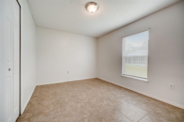 tiled empty room featuring a textured ceiling