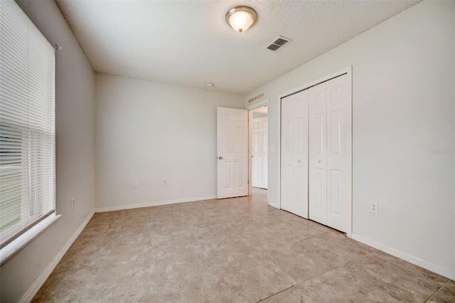 unfurnished bedroom featuring a closet, a textured ceiling, and light tile flooring