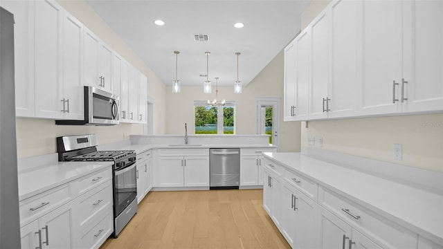 kitchen with kitchen peninsula, stainless steel appliances, sink, pendant lighting, and white cabinetry