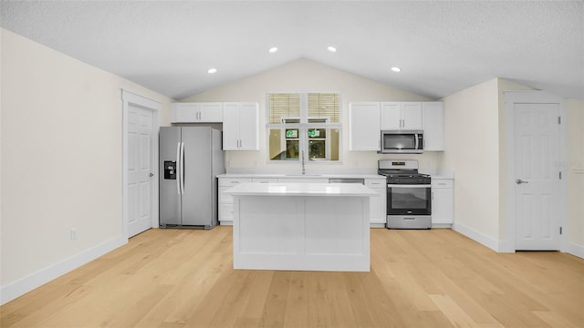 kitchen with white cabinets, stainless steel appliances, light hardwood / wood-style flooring, and a kitchen island