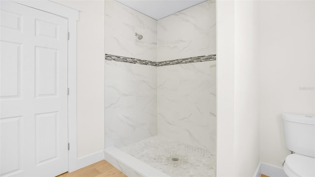 bathroom with a tile shower, hardwood / wood-style flooring, and toilet