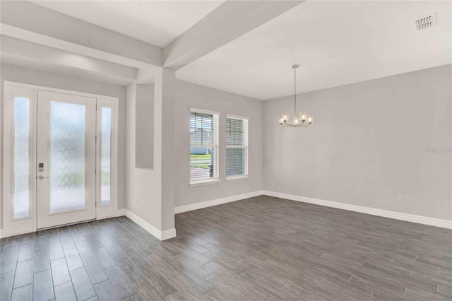 entrance foyer with an inviting chandelier and dark hardwood / wood-style flooring