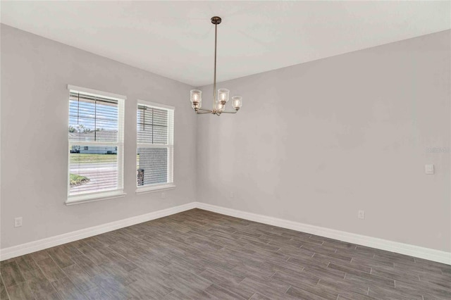 unfurnished room with a chandelier and dark hardwood / wood-style floors