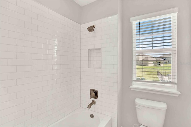 bathroom with tiled shower / bath combo and toilet