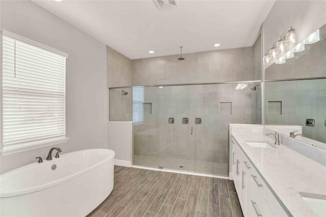 bathroom featuring plenty of natural light, double vanity, and separate shower and tub