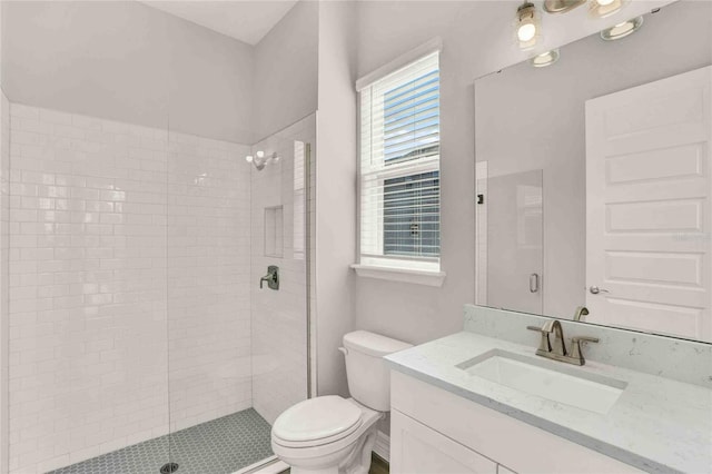 bathroom featuring toilet, a shower with shower door, and vanity