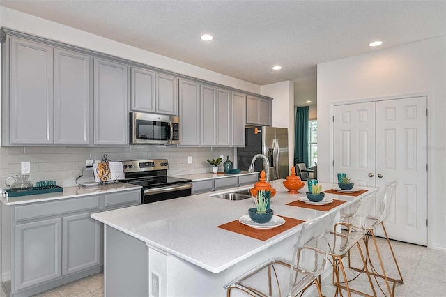 kitchen featuring a kitchen bar, sink, appliances with stainless steel finishes, and an island with sink