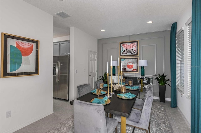 dining area featuring light tile patterned floors and a textured ceiling