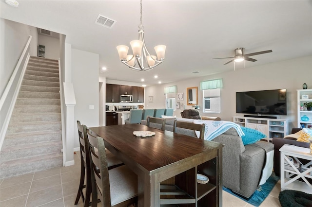 tiled dining space with ceiling fan with notable chandelier