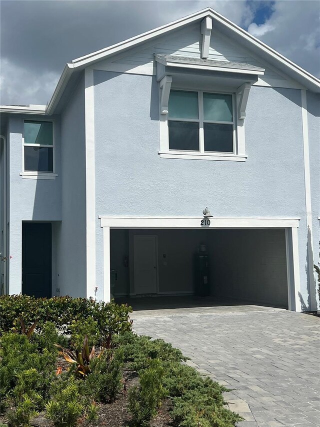 view of front of property featuring a garage, decorative driveway, and stucco siding