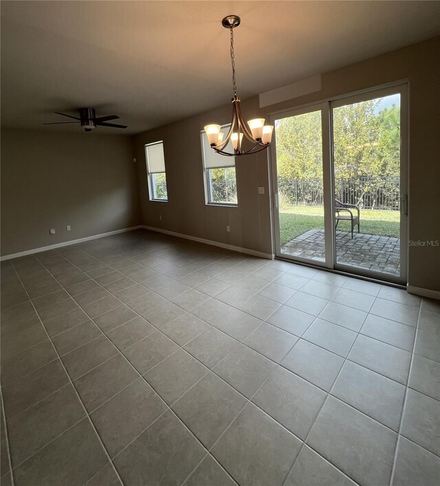 tiled spare room featuring baseboards and ceiling fan with notable chandelier