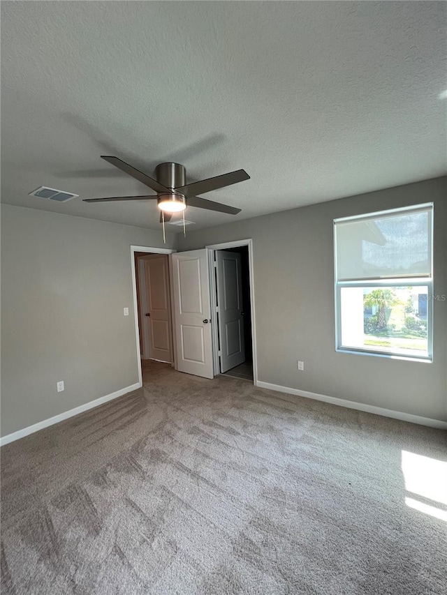 unfurnished bedroom featuring baseboards, visible vents, a textured ceiling, and light colored carpet