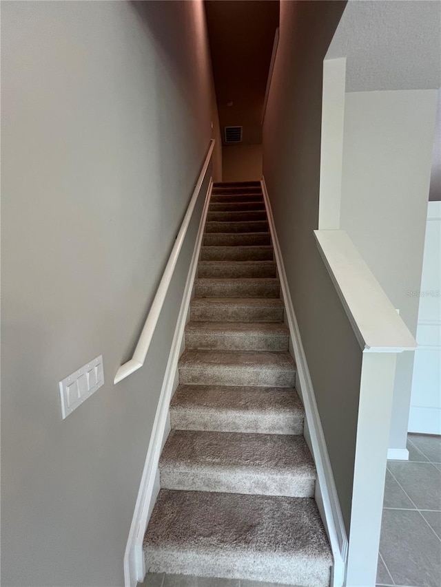 stairs with baseboards, visible vents, and tile patterned floors