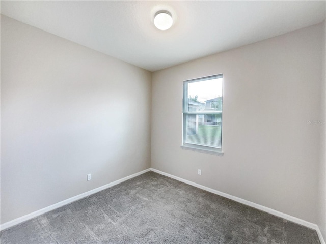 spare room with dark colored carpet