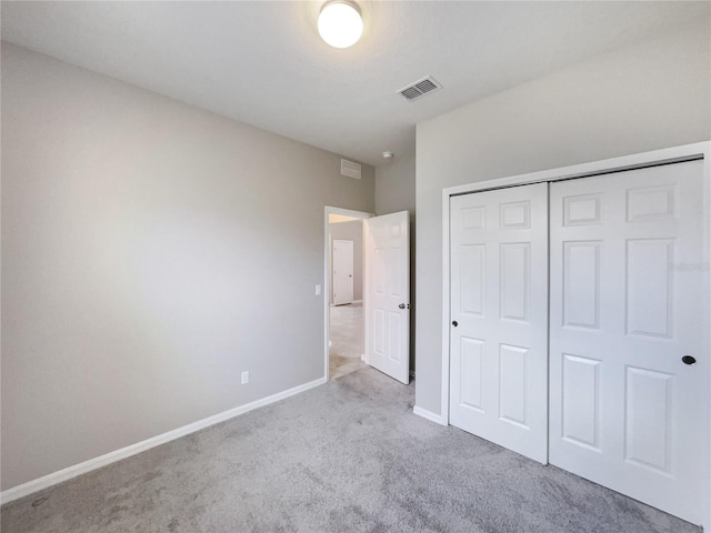 unfurnished bedroom featuring light carpet and a closet