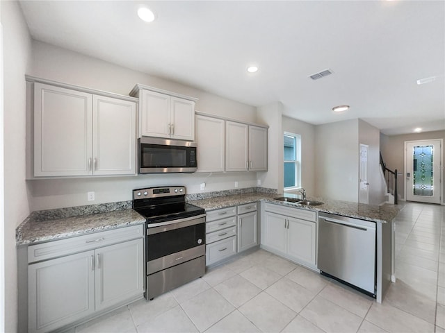 kitchen featuring light stone counters, appliances with stainless steel finishes, light tile floors, and sink