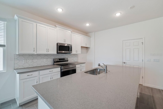 kitchen featuring appliances with stainless steel finishes, white cabinets, and a center island with sink