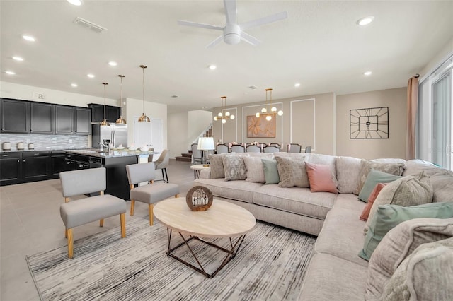 tiled living room with sink and ceiling fan with notable chandelier