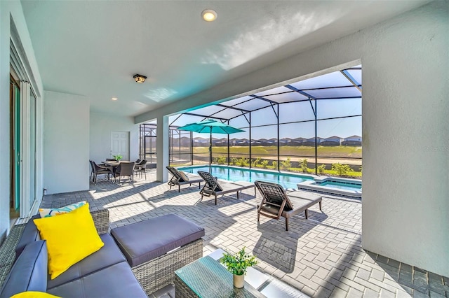 view of patio / terrace featuring a swimming pool with hot tub, a lanai, and an outdoor hangout area