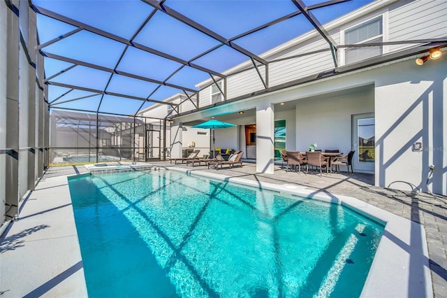 view of pool featuring an in ground hot tub, a patio area, and glass enclosure