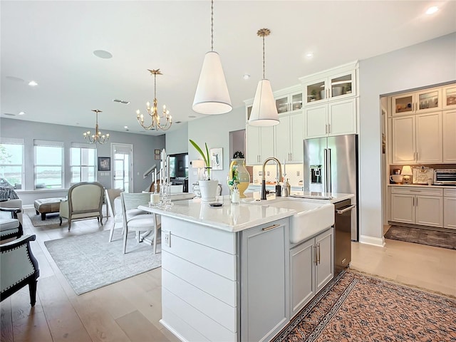 kitchen featuring light hardwood / wood-style flooring, an island with sink, backsplash, and hanging light fixtures