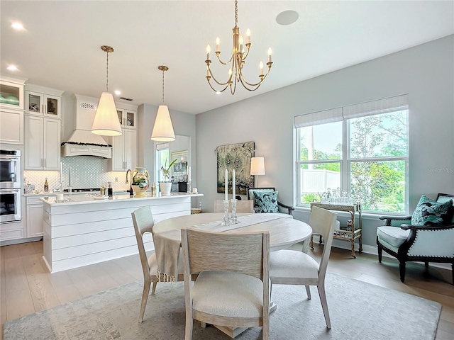 dining room featuring sink, light hardwood / wood-style floors, and a notable chandelier