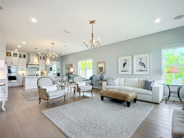 living room with light wood-type flooring and a chandelier