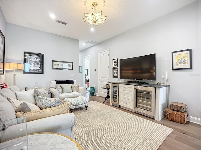 living room with indoor bar, beverage cooler, and hardwood / wood-style floors