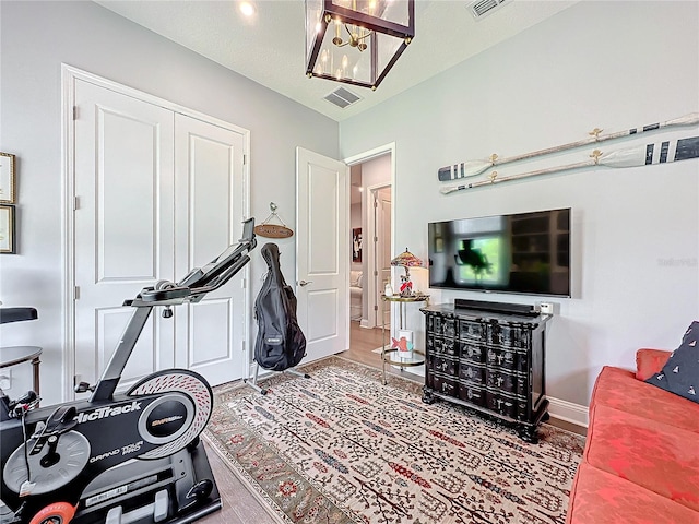 exercise area with hardwood / wood-style floors and an inviting chandelier