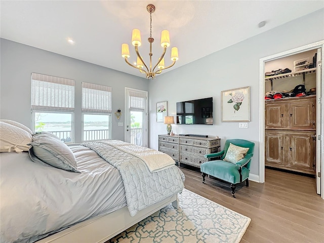 bedroom featuring multiple windows, a chandelier, and light hardwood / wood-style flooring