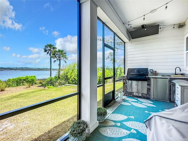 sunroom featuring sink and a water view