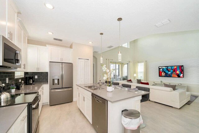 kitchen with white cabinetry, decorative light fixtures, sink, an island with sink, and stainless steel appliances