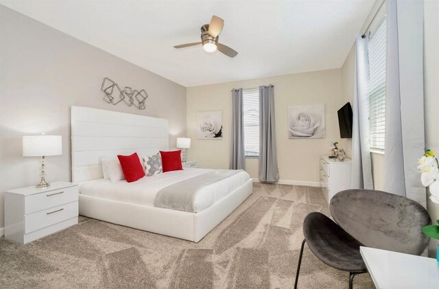 bedroom featuring light carpet, ceiling fan, and multiple windows