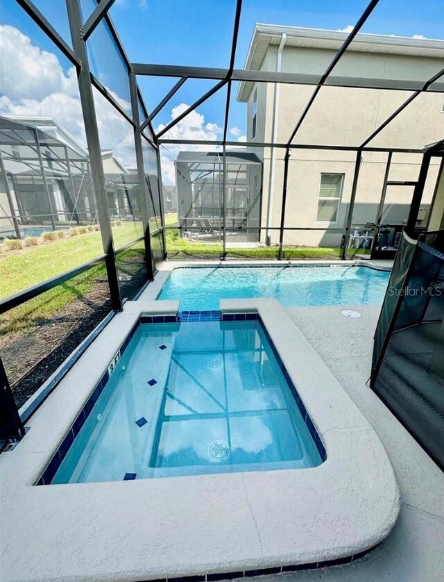 view of swimming pool featuring glass enclosure and a patio