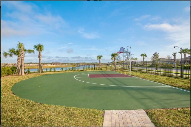 view of sport court featuring a water view and a yard