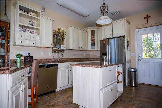 kitchen with a center island, pendant lighting, white cabinetry, stainless steel appliances, and dark tile flooring