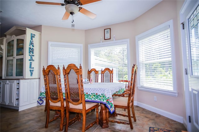 dining area featuring a wealth of natural light, ceiling fan, and dark tile floors