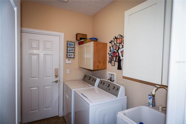 washroom featuring washer and clothes dryer, washer hookup, sink, dark tile flooring, and cabinets