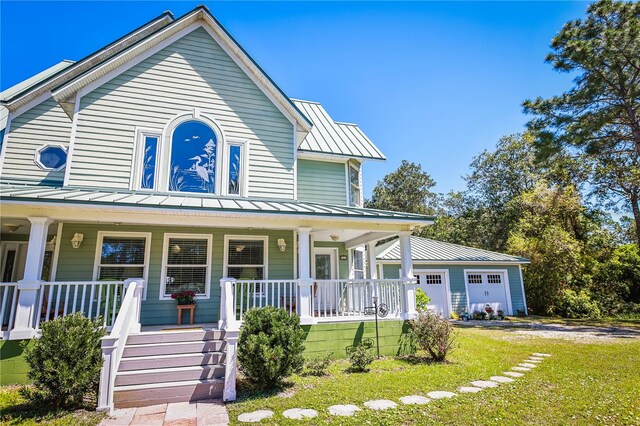 view of front facade featuring a front lawn, covered porch, and a garage