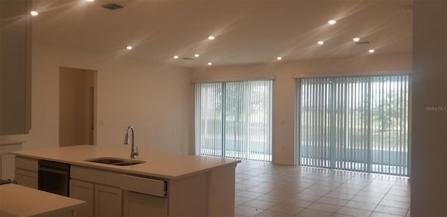 kitchen with white cabinetry, sink, light tile patterned flooring, and a kitchen island with sink