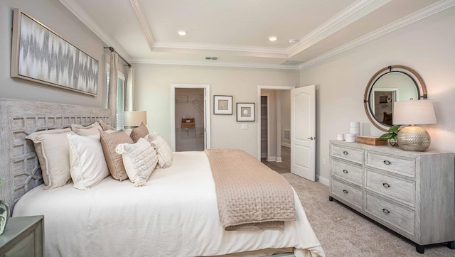 carpeted bedroom featuring a raised ceiling, ornamental molding, and a walk in closet