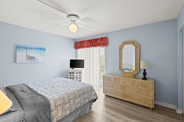 bedroom with ceiling fan, hardwood / wood-style flooring, and a textured ceiling