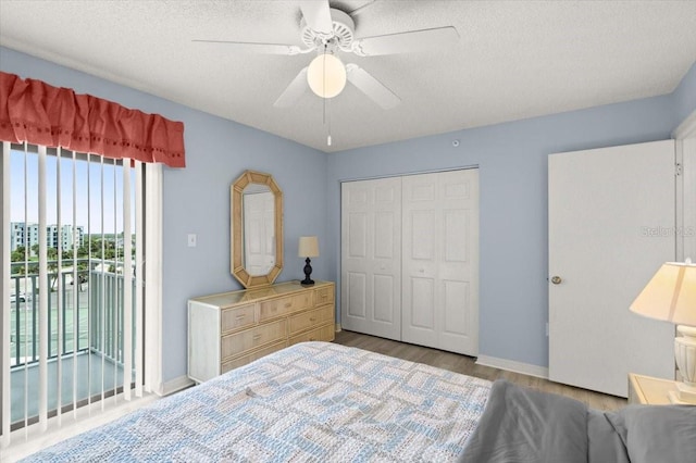 bedroom featuring a closet, light hardwood / wood-style floors, access to exterior, a textured ceiling, and ceiling fan