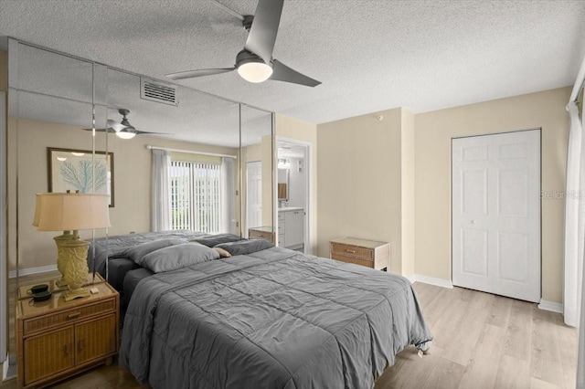 bedroom featuring light hardwood / wood-style flooring, connected bathroom, ceiling fan, and a textured ceiling