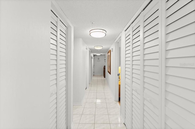 hallway featuring a textured ceiling and light tile patterned flooring