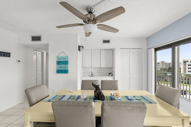 dining space with a textured ceiling, light tile patterned flooring, and ceiling fan