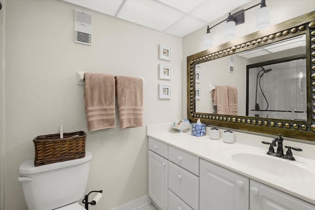 bathroom with walk in shower, vanity, a paneled ceiling, and toilet