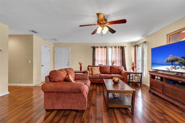 living room featuring dark wood-type flooring, ceiling fan, and a textured ceiling