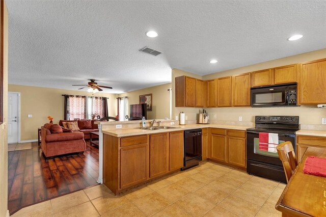 kitchen featuring kitchen peninsula, ceiling fan, black appliances, light wood-type flooring, and a textured ceiling